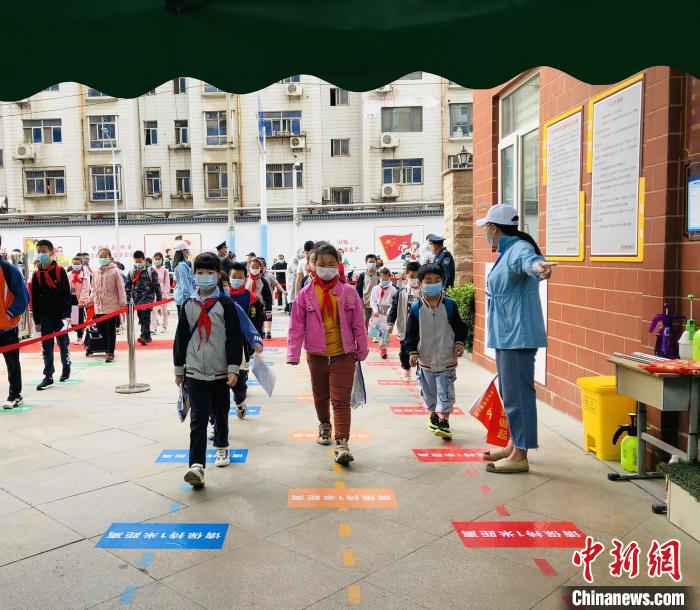郑州市金水区金燕小学的小学生脚踩一米间隔线排队入校 杨晨 摄