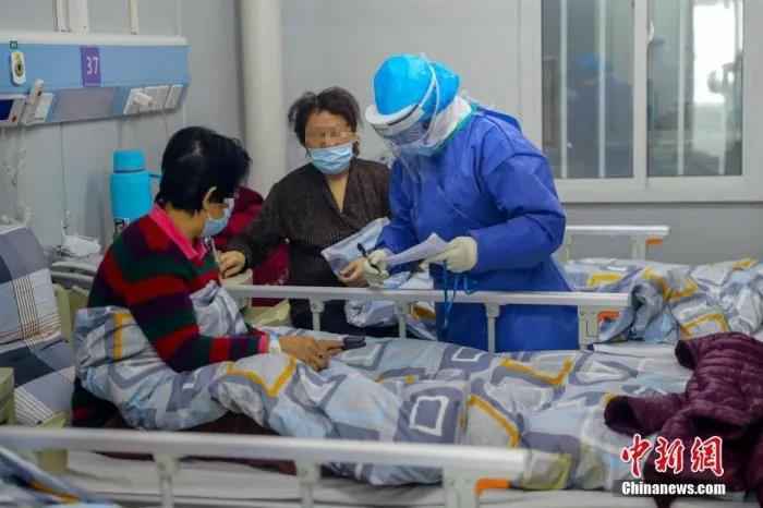资料图：武汉火神山医院感染二科一病区的隔离病房内护士长胡晶为患者进行身体检查。/p中新社记者 张畅 摄