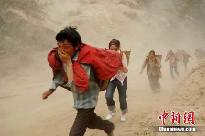 2008年5月20日，汶川震区民众快速通过山体滑坡险段。/p中新社记者 陈文 摄