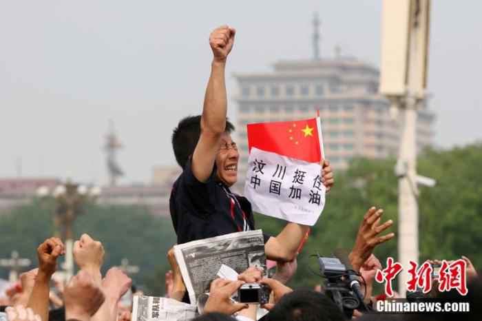 2008年5月19日，北京天安门广场上的民众为地震遇难者默哀，一位来自四川的男子高举右手为家乡加油。/p中新社记者 富田 摄