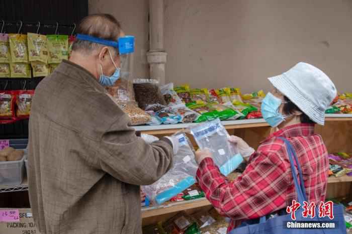 当地时间5月18日，一位老人在美国旧金山华埠一处店铺外的摊位前购买防疫物品。/p中新社记者 刘关关 摄