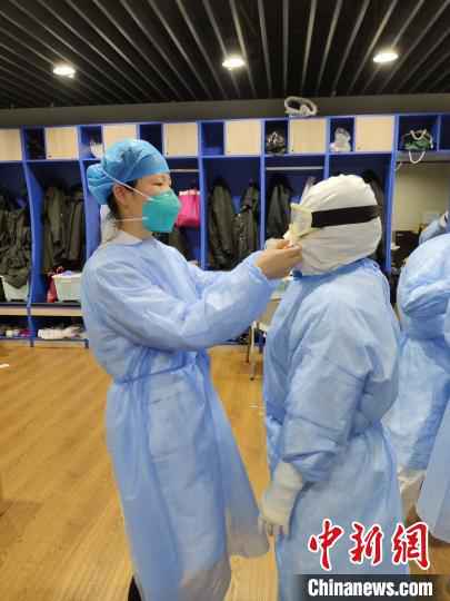 在武昌方舱医院，梁艳冰帮队员整理防护服。　受访者供图 摄