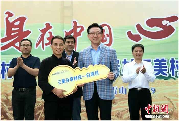 唐文德(前左)从中国三星总裁黄得圭(前右)手中接过象征希望的金钥匙。
