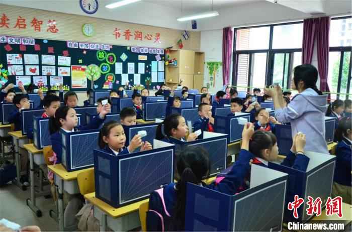 郑东新区蒲公英小学的老师向学生演示如何折叠废弃口罩。　齐乃莹 摄