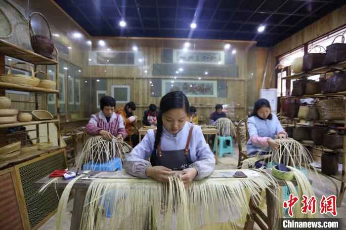 图为杨昌芹带领手工艺人们加紧编制竹工艺品。　王长育 摄