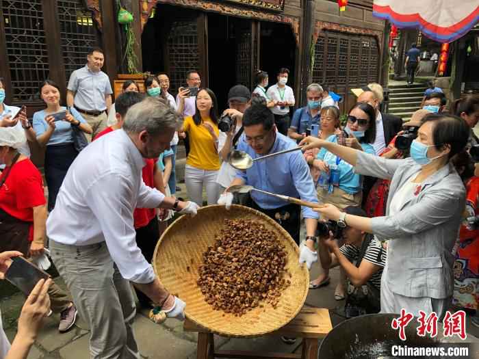 图为外国友人体验怪味胡豆穿糖衣。　钟旖 摄