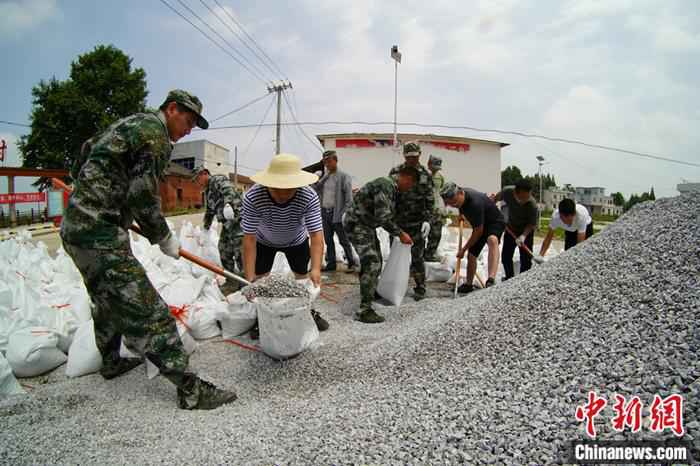 7月14日，退伍军人在棉船镇江心村装填抗洪沙袋。王昊阳 摄