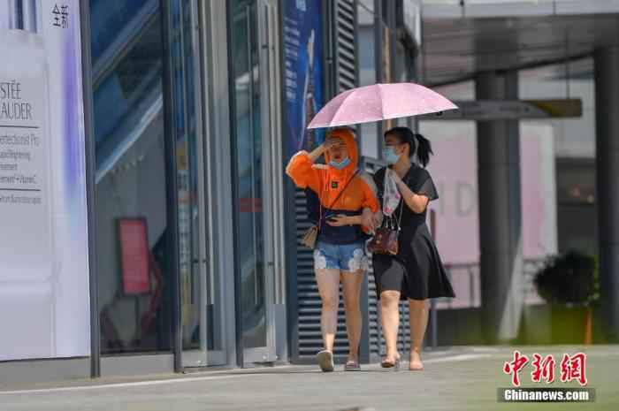 资料图：民众冒高温撑伞出行。 骆云飞 摄