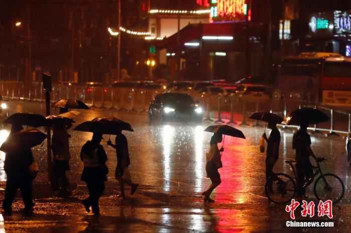 资料图：市民冒雨出行。/p中新社记者 盛佳鹏 摄