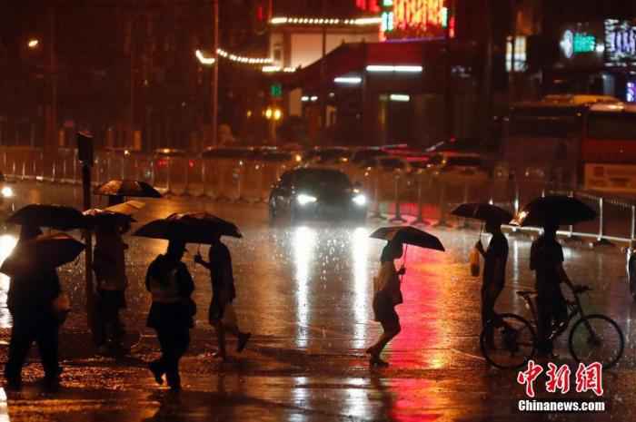 资料图：市民冒雨出行。/p中新社记者 盛佳鹏 摄
