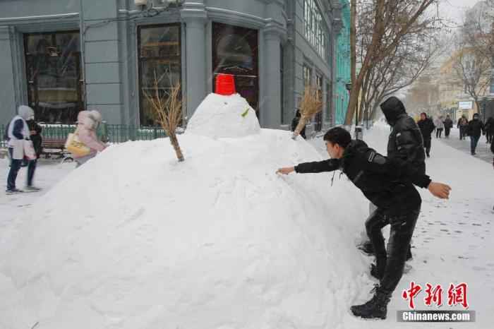 资料图：11月19日，黑龙江省哈尔滨市迎来大暴雪天气，虽给当地市民交通出行带来不便，但也营造了银装素裹的冬季美景。图为中央大街上的雪人吸引游客。 /p中新社记者 吕品 摄