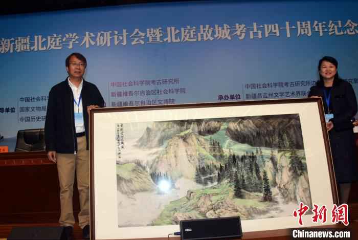 开幕式上，陈星灿(左)代表中国社会科学院考古研究所接受新疆昌吉州赠送的绘画作品。　孙自法 摄