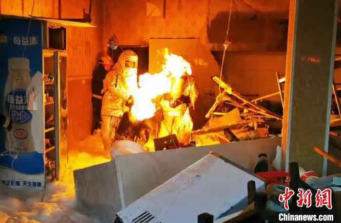 一名消防救援人员在泡沫水枪掩护下，三进厨房拎出煤气罐。湖北咸宁消防供图