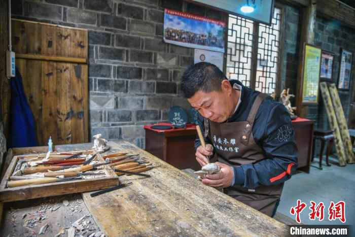 浙江台州“章安木雕”非遗传承人王林杰在章安老街上创作木雕 范宇斌 摄