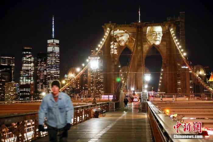 当地时间3月14日晚，美国纽约市政府将因新冠肺炎去世的患者面容投影在布鲁克林大桥桥身上，表达对逝者的怀念。当晚，纽约市举行活动纪念因新冠肺炎去世的患者。 /p中新社记者 廖攀 摄