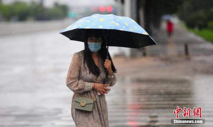 资料图：市民冒雨出行。
/p中新社记者 于海洋 摄