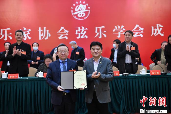 中国音协分党组书记、驻会副主席韩新安(右)为小提琴演奏家、中央歌剧院院长刘云志(左)颁发弦乐学会会长聘书。中国音协供图