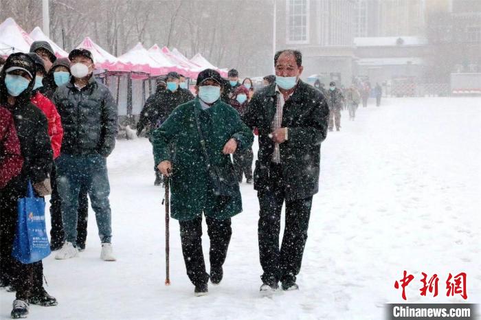 老人相互搀扶走在雪中 滕明月 摄