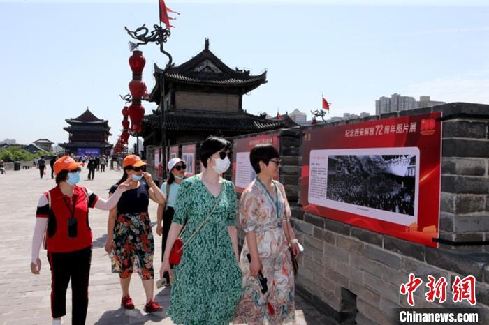 图为民众驻足观看“纪念西安解放72周年图片展”。　西安城墙 供图