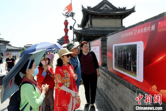 图为民众驻足观看“纪念西安解放72周年图片展”。　西安城墙 供图