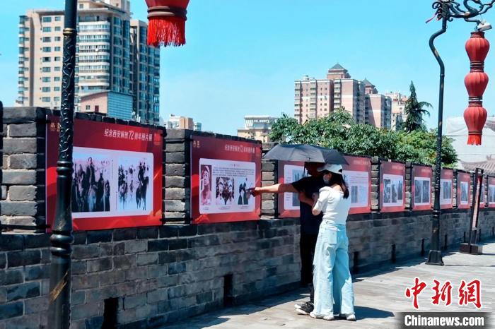 图为民众驻足观看“纪念西安解放72周年图片展”。　西安城墙 供图