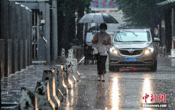 7月12日，北京朝阳区团结湖附近，市民冒雨出行。 /p中新社记者 贾天勇 摄