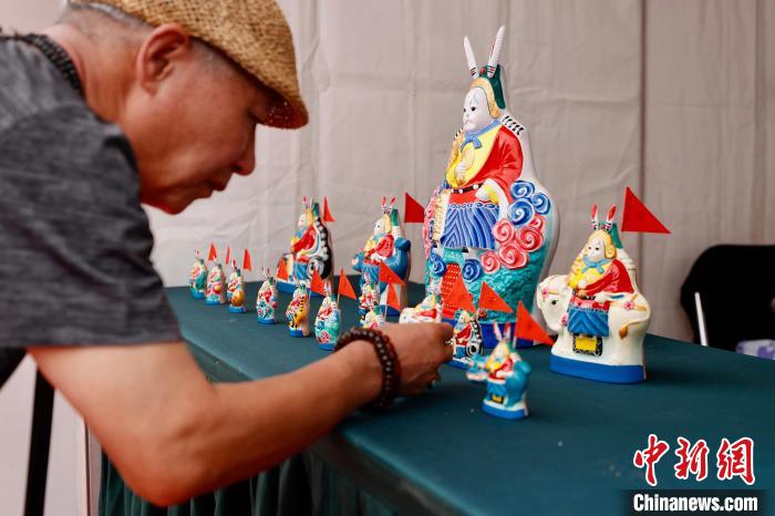 15日，中国潘家园第一届非遗文化节在北京潘家园旧货市场开幕。图为游客在泥彩塑兔儿爷展位前驻足。　/p中新社记者 富田 摄