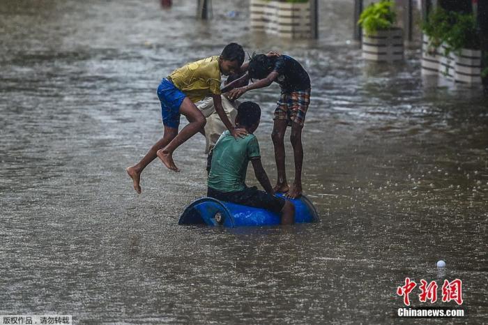 资料图：当地时间6月9日，印度孟买遭遇暴雨天气，街道被积水淹没。图为孩子们在被水淹没的街上玩耍。