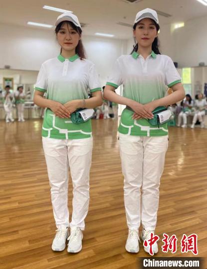 二名青年志愿者穿着志愿者服装“檐上飞花”在福州参加世遗大会形象礼仪培训。　受访者供图