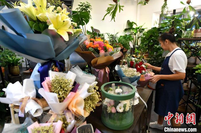 资料图：随着七夕(8月14日)“情人节”临近，为了抓住这一难得的销售旺季，福州不少商家已经开始忙碌起来，积极备货抢占七夕鲜花市场。图为店员正在整理花束。　吕明 摄