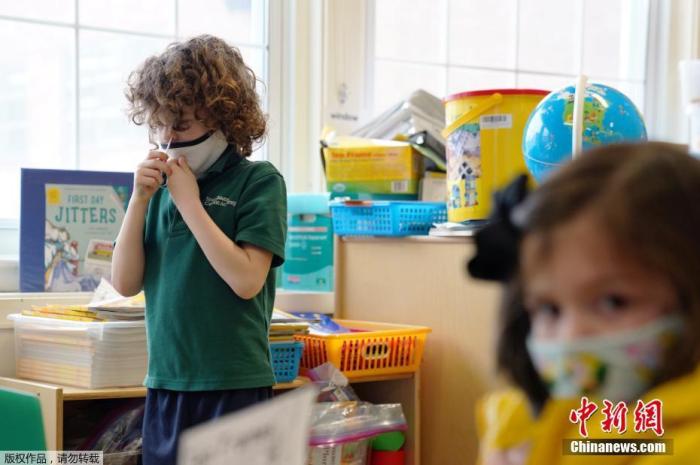 资料图：美国马萨诸塞州波士顿市一所学校内，小学生们佩戴口罩在教室学习。在此期间，学校老师要求孩子各自进行核酸检测。
