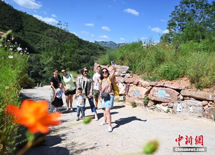 8月25日，旅客来到名为“伴山邀”的石窟民宿旁游玩自拍。(资料图片) /p中新社记者 翟羽佳 摄 　